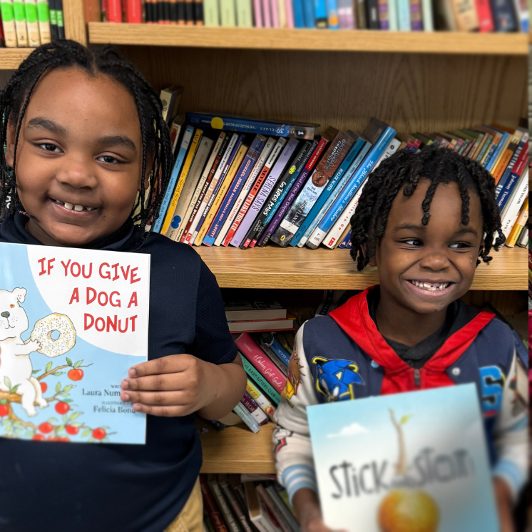 Two Joseph Pennell Elementary School students smiling while holding books in the school library, celebrating reading and literacy achievement.