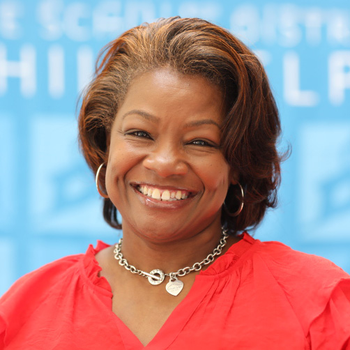 Portrait of Susan Lofton, Principal of Joseph Pennell Elementary School, smiling and wearing a red blouse against a blue background.